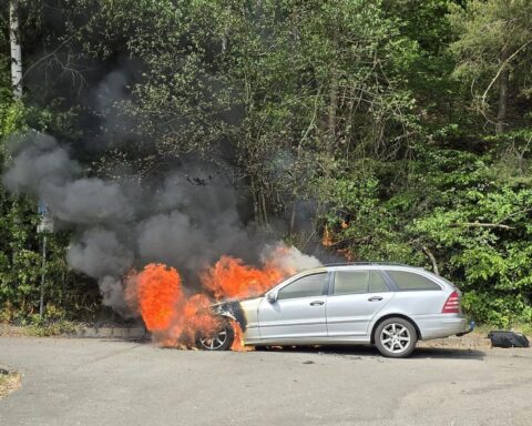 Ein Mercedes-Fahrzeug steht in Flammen, Feuerwehr löscht Brand, Fahrer entkommt unverletzt.