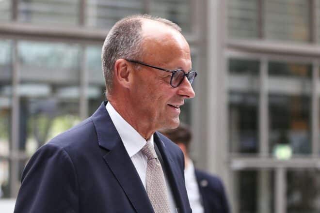 Friedrich Merz im Vordergrund, im Hintergrund Koalitionsgespräche zwischen Union und SPD skizziert.