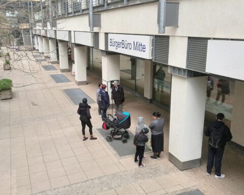 Menschen vor Bürgerbüro warten auf Einbürgerung, symbolisieren neuen Einbürgerungsrekord in Deutschland.