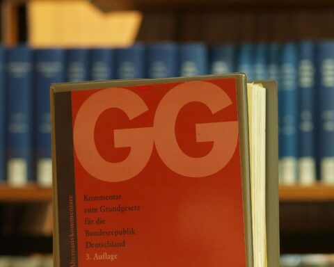 Eine Bibliothek mit offenem Grundgesetz, symbolisiert Freiheit, Menschenwürde und demokratische Werte.