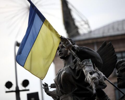 Ukrainische Flagge vor militärischem Hintergrund, symbolisiert Rüstungsinvestitionen und technologische Zusammenarbeit.