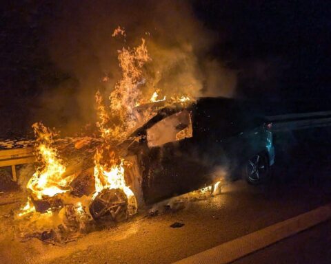 Ein brennendes Auto auf der Autobahn mit Feuerwehr im Einsatz und gelöscht.