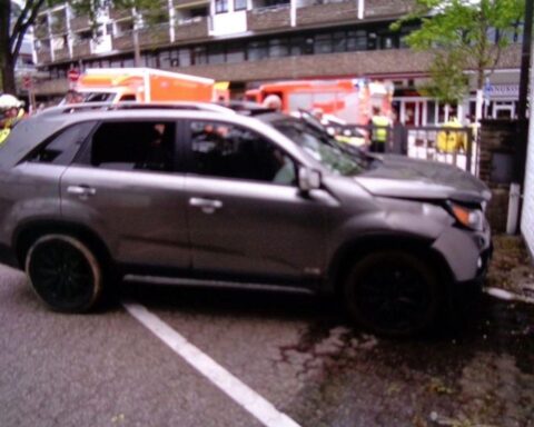 Verunfallter grauer Kia vor beschädigter Hauswand in Bensberg, Feuerwehr und Polizei sichern die Szene.