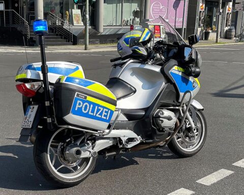Ein Polizeimotorrad vor einem Unfallort, symbolisch für Verkehrssicherheit und Polizisten im Einsatz.