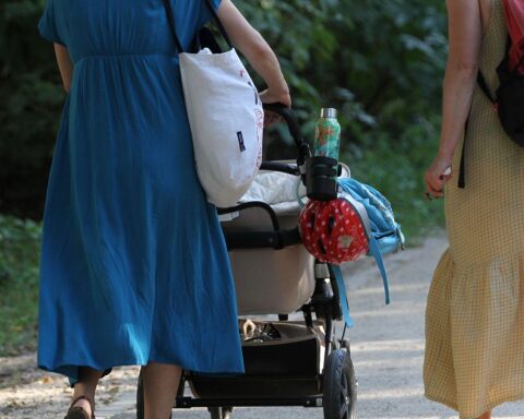 Zwei Frauen mit Kinderwagen diskutieren die möglichen Elterngeldkürzungen in Berlin.