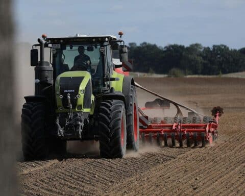 Bauer mit Traktor auf dem Feld, symbolisiert Landwirtschaft und Biokraftstoffproduktion in Deutschland.