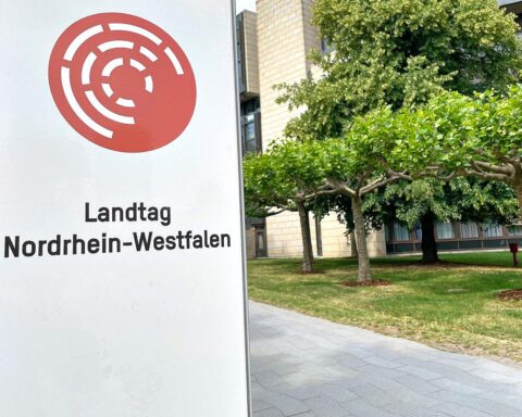 Landtag Nordrhein-Westfalen mit Finanzsymbolen und positiven Bewertungen, die finanzielle Stabilität betonen.
