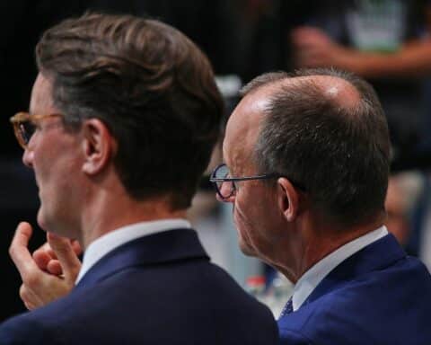 Hendrik Wüst und Friedrich Merz stehen zusammen, symbolisieren politischen Austausch und Spekulationen über Kanzlertausch.