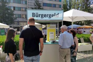 Passanten informieren sich an einem Infostand über Bürgergeld und Mobilitätsleistungen in Berlin.
