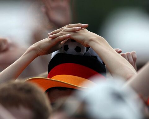 Fußballfan mit schwarz-rot-goldener Fan-Ausrüstung, jubelnd während der Weltmeisterschaft.