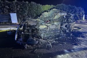 Schwerer Verkehrsunfall mit brennendem Auto, Feuerwehr im Einsatz, Verletzte werden versorgt.