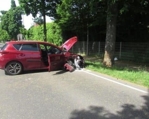 Junge Frau hat Autounfall; Toyota kollidiert mit Baum, Feuerwehr sichert Unfallstelle.