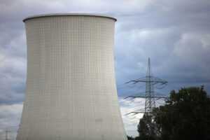 Kernkraftwerk im Hintergrund, Solar- und Windkraftanlagen im Vordergrund, symbolisiert den Energiewandel.