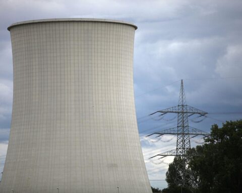 Kernkraftwerk im Hintergrund, Solar- und Windkraftanlagen im Vordergrund, symbolisiert den Energiewandel.