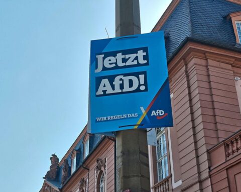 Ein AfD-Plakat vor einem Hintergrund mit wirtschaftlicher Förderung und Infrastrukturentwicklung.