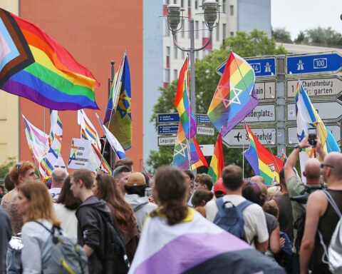 Bunte Parade mit LGBTIQ-Flaggen, Feiern und Menschen, die Gleichberechtigung und Akzeptanz symbolisieren.