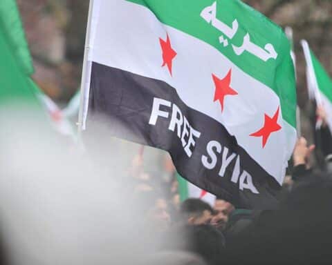 Syrische Flüchtlinge feiern den Sturz von Assad in Deutschland mit fröhlicher Stimmung und Fahnen.