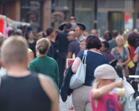 Menschen in einer belebten Fußgängerzone, die über Steuern und soziale Gerechtigkeit diskutieren.