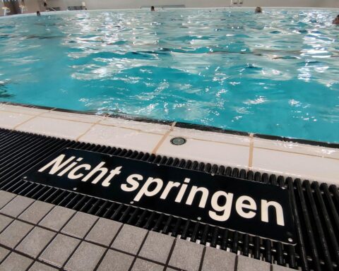 Leeres Schwimmbad mit wenigen Bademeistern und modernem Überwachungssystem für Sicherheit.