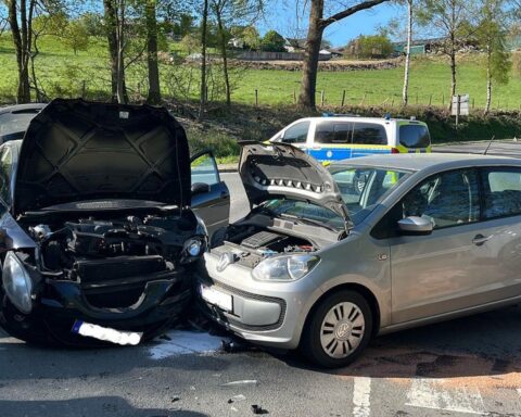 Zwei beschädigte Autos nach Verkehrsunfall, Polizei und Abschleppwagen vor Ort.
