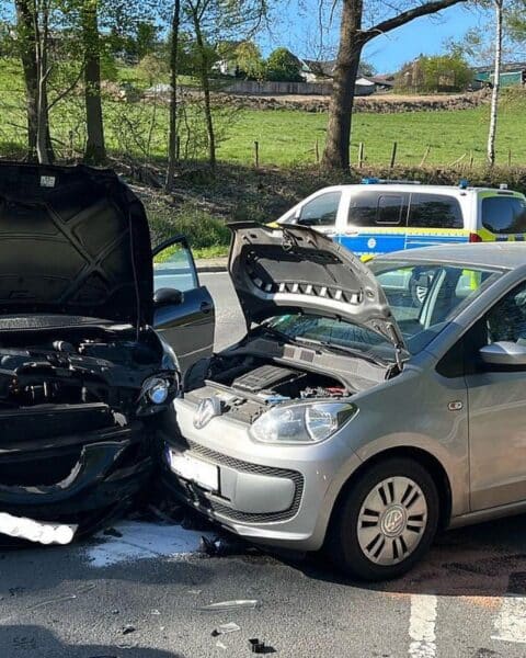 Zwei beschädigte Autos nach Verkehrsunfall, Polizei und Abschleppwagen vor Ort.