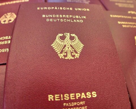 Ein Reisepass auf einem Schreibtisch, umrahmt von Dokumenten und politischen Symbolen.
