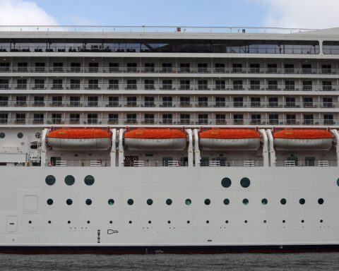 Kreuzfahrtschiff im Hafen mit Rettungsbooten, symbolisiert steigende Beliebtheit von Hochsee-Reisen.