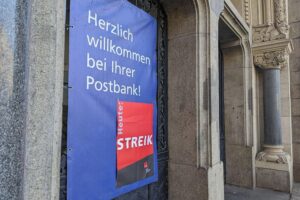 Streik-Hinweis an Postbank-Filiale zeigt Protest gegen unzureichende Gehaltserhöhungen und Arbeitsbedingungen.
