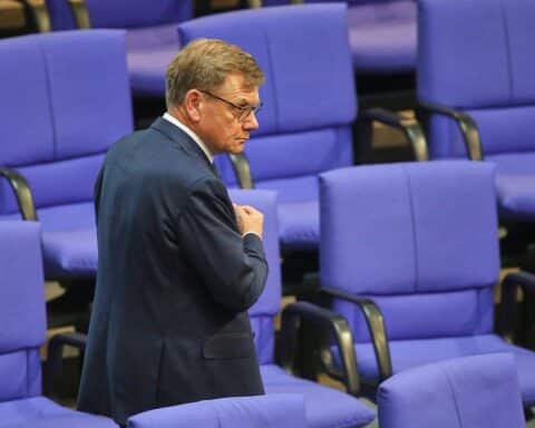 Johann Wadephul steht vor einem EU-Flaggenhintergrund, symbolisiert Partnerschaft und kritische Diskussionen.