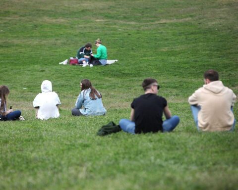 Junge Leute entspannen im Park bei sonnigem Wetter und sommerlichen Temperaturen.