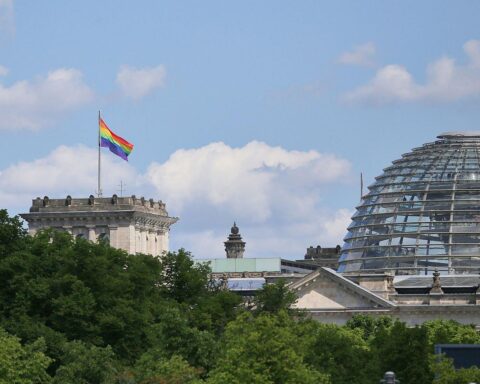 Regenbogenflaggen am Reichstag im sonnigen Berlin, Symbol für Vielfalt und Toleranz.