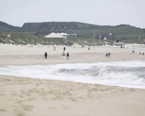 Sonniger Sylter Strand, glückliche Menschen, entspannte Atmosphäre, frühsommerliches Wetter, sanfte Wellen.