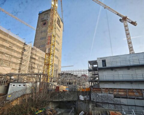 Baustelle mit Hochhauskränen, sonnigem Himmel und Menschen, die aktiv arbeiten oder entspannen.