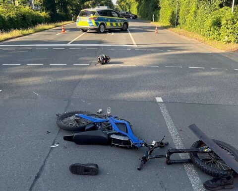 Kreuzungsunfall: beschädigtes Kleinkraftrad und Unfallstelle mit Rettungswagen, Polizei vor Ort.