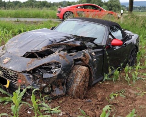 Verunglückter Sportwagen auf einem Feld, Polizeiabsperrung, leichte Schäden sichtbar.