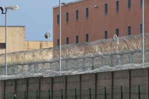 Gefängniszelle mit Justizsymbolik, um den Haftbefehl und die Tat zu verdeutlichen.
