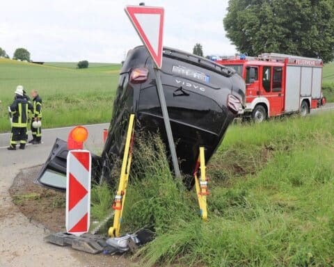 Ein schwarzer Dacia liegt nach Unfall auf dem Dach im Straßengraben.