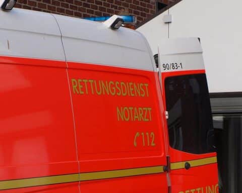 Rettungswagen vor Unfallstelle, symbolisiert medizinischen Notfall und schwere Verletzungen einer Autofahrerin.