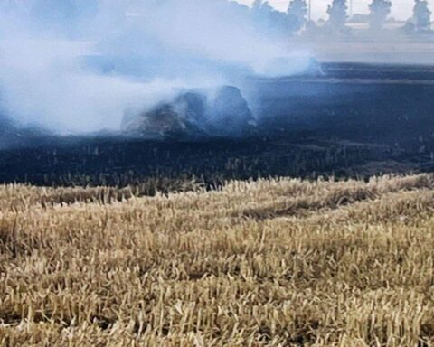 Brennende Ballenpresse auf einem Feld; Feuerwehr im Einsatz, hoher Sachschaden, keine Verletzten.