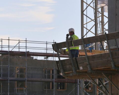 Bauarbeiter auf Baustelle diskutieren neue Ansätze zur Senkung der Baukosten in Deutschland.