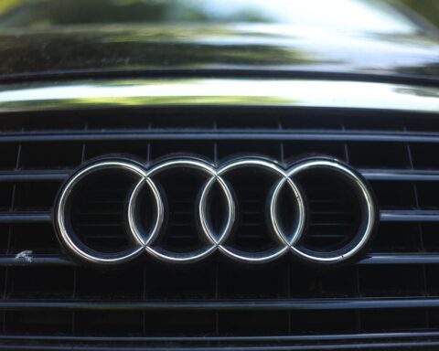 Audi-Logo mit Fahrzeugen, Symbol für sinkende Absatzziele und Herausforderungen im Wirtschaftsumfeld.