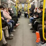 Vollbesetzte U-Bahn mit Menschen in Masken während der Corona-Pandemie, symbolisiert Unsicherheit und Gesundheitsrisiken.