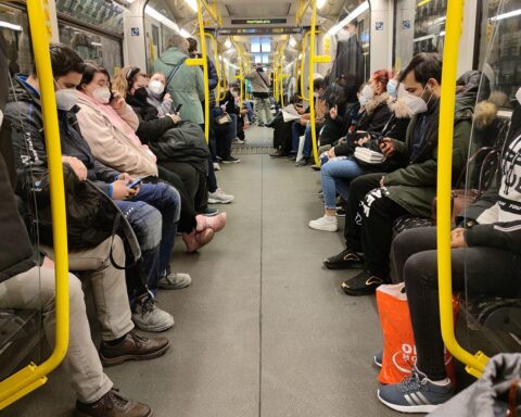 Vollbesetzte U-Bahn mit Menschen in Masken während der Corona-Pandemie, symbolisiert Unsicherheit und Gesundheitsrisiken.