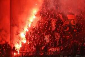 Fans zünden Pyrotechnik in einem Stadion, während Sicherheitsmaßnahmen diskutiert werden.