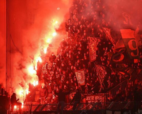 Fans zünden Pyrotechnik in einem Stadion, während Sicherheitsmaßnahmen diskutiert werden.