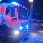Feuerwehr im Einsatz nach explosivem Wohnungsbrand, Anwohner helfen, Gebäude stark beschädigt.