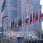 Fahnen der Vereinten Nationen vor dem Hintergrund eines internationalen politischen Kontextes.