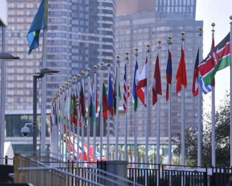 Fahnen der Vereinten Nationen vor dem Hintergrund eines internationalen politischen Kontextes.