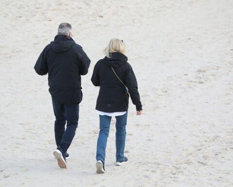 Paar spaziere am Strand, symbolisiert familiäre Zusammenhalt und zukünftige gesundheitspolitische Herausforderungen.