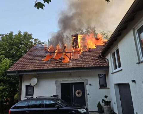 Dachstuhlbrand mit Feuerwehr im Einsatz, Einsatzkräfte löschen flammenden Brand und sichern Gebäude.